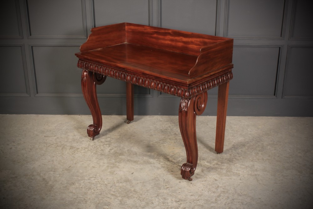 A William IV mahogany console table featuring a raised gallery back, gadrooned edge detailing, and bold S-scroll front legs on brass castors. View VIII