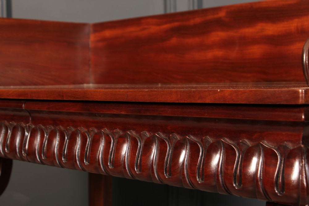 A William IV mahogany console table featuring a raised gallery back, gadrooned edge detailing, and bold S-scroll front legs on brass castors. View XIII