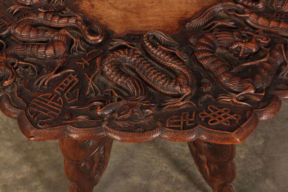 An octagonal dark hardwood occasional table featuring deep relief dragon carvings across the tabletop and legs. View III