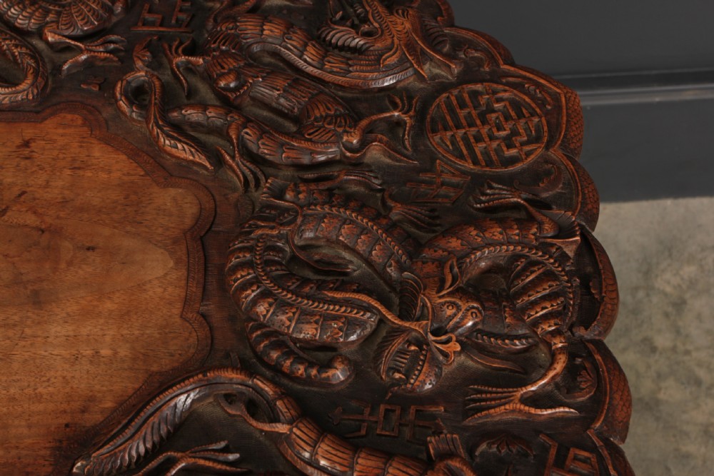 An octagonal dark hardwood occasional table featuring deep relief dragon carvings across the tabletop and legs. View IV