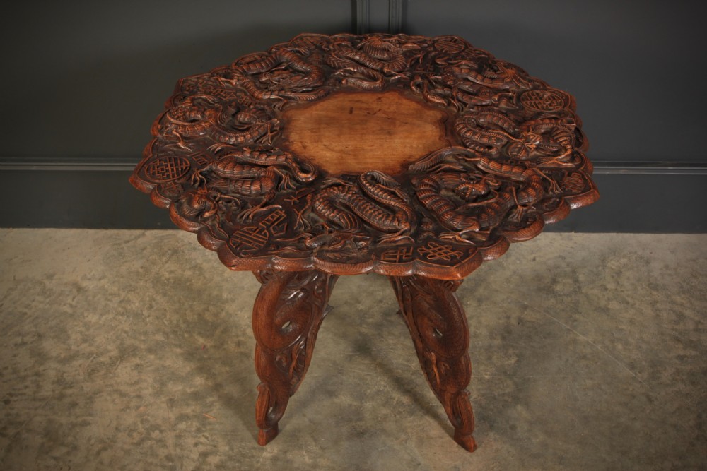 An octagonal dark hardwood occasional table featuring deep relief dragon carvings across the tabletop and legs. View VI