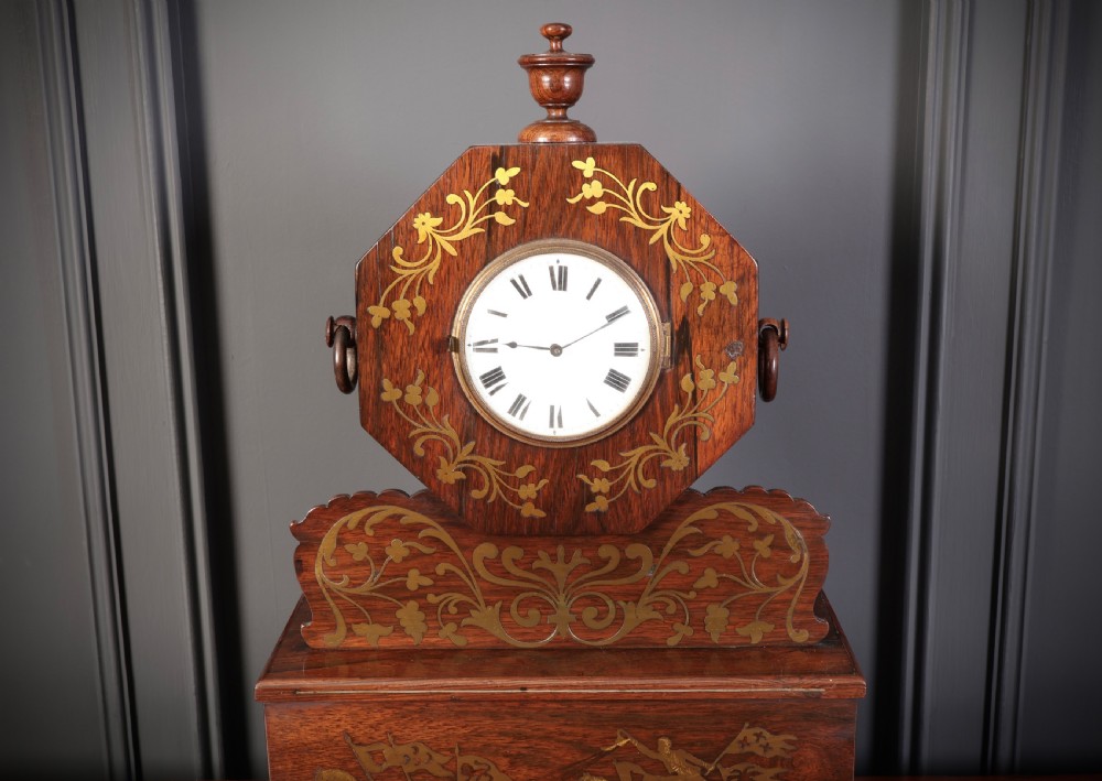 A Regency dark rosewood mantel clock with intricate brass inlay, an octagonal dial surround, and an equestrian brass scene on the base plinth. View II