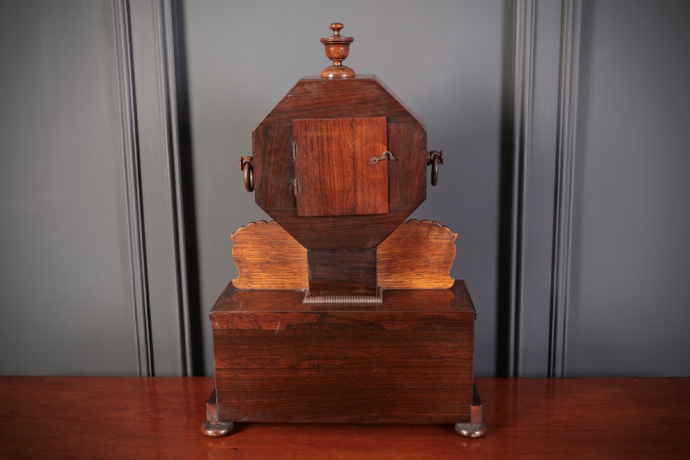 A Regency dark rosewood mantel clock with intricate brass inlay, an octagonal dial surround, and an equestrian brass scene on the base plinth. View VIII