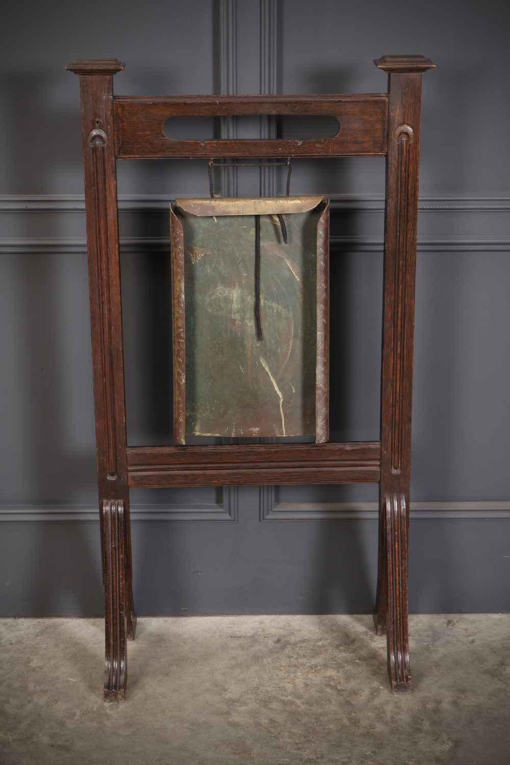 A freestanding dark oak frame housing a suspended rectangular hammered brass dinner gong complete with a wooden striker. View IX