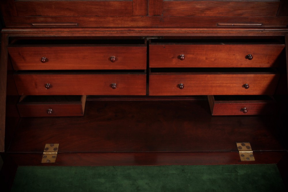 A George III mahogany bureau bookcase featuring two glazed doors on the upper section above a slant-front bureau and four graduated drawers with brass handles. View VI