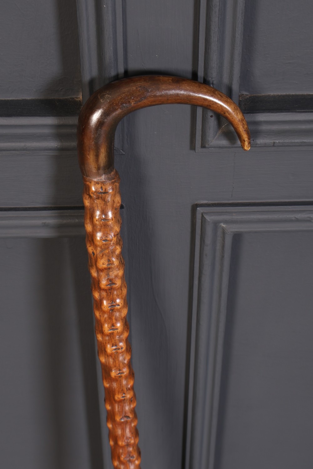 A wooden walking stick featuring a smooth curved crook handle and a textured shaft with natural wood knots. View II