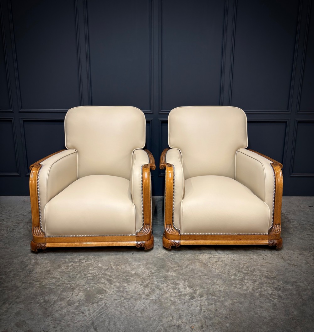 An Art Deco three-piece suite featuring a three-seater sofa and two armchairs upholstered in cream leather with polished walnut trim and stud details. View III