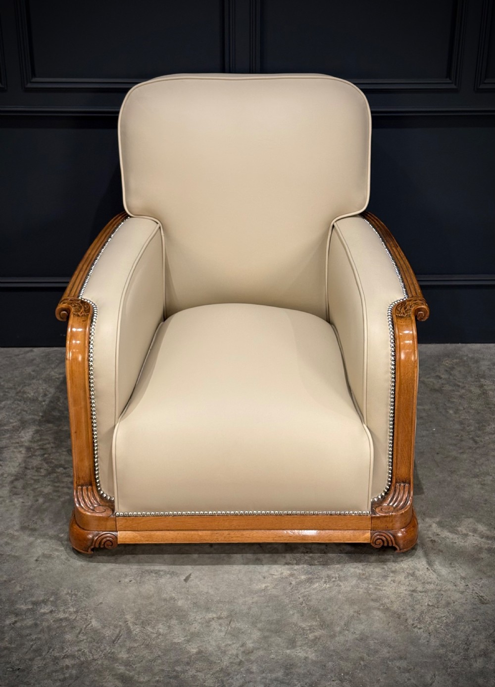 An Art Deco three-piece suite featuring a three-seater sofa and two armchairs upholstered in cream leather with polished walnut trim and stud details. View VIII