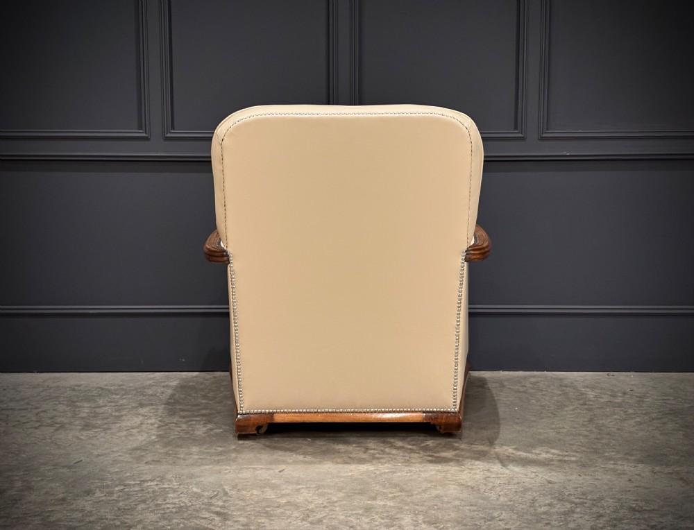 An Art Deco three-piece suite featuring a three-seater sofa and two armchairs upholstered in cream leather with polished walnut trim and stud details. View XII