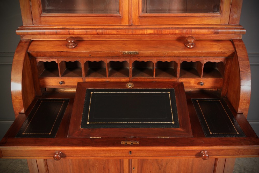 A Victorian warm brown walnut cylinder bureau bookcase featuring a two-door glazed upper cabinet over a curved roll-top desk section and lower cupboard base. View X