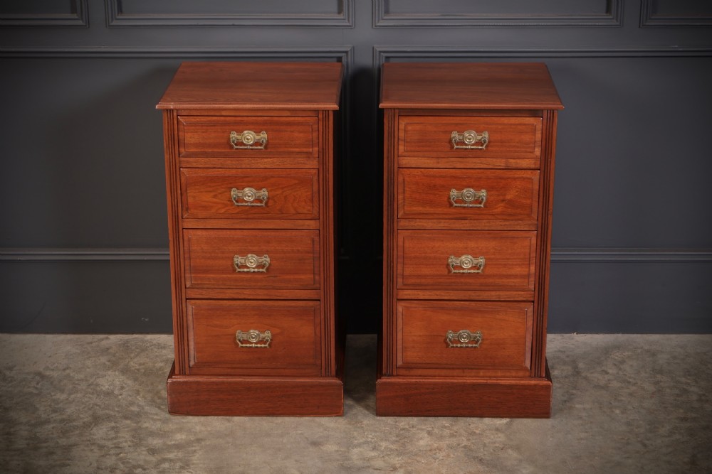 A pair of late Victorian walnut bedside chests, each featuring four drawers with ornamental brass handles on a plinth base. View II