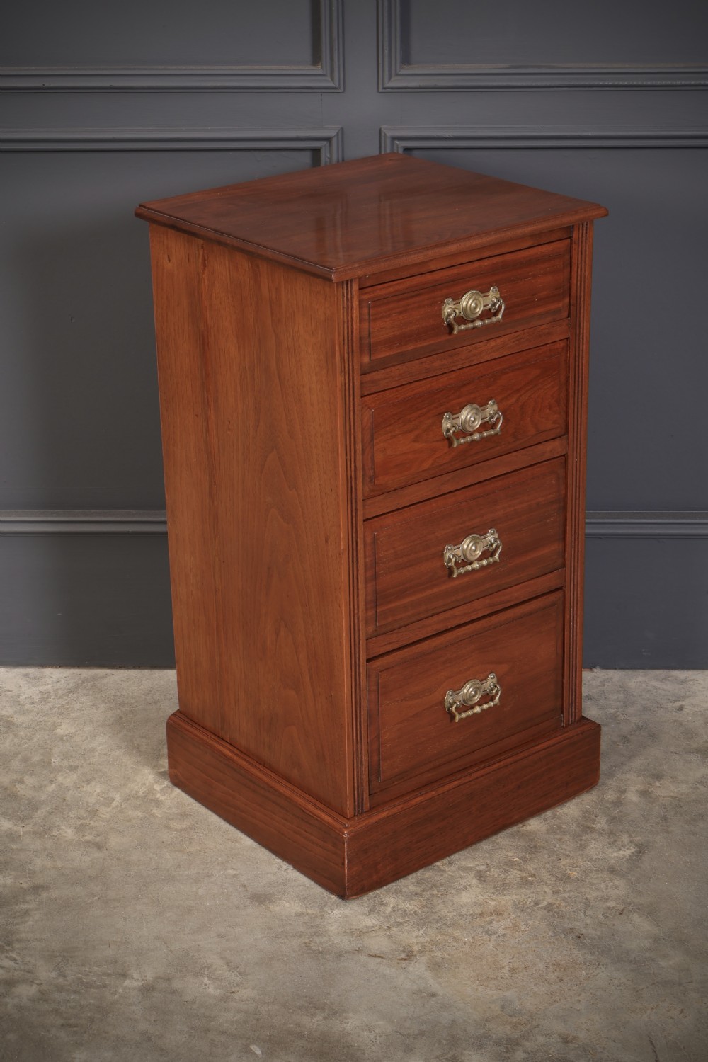 A pair of late Victorian walnut bedside chests, each featuring four drawers with ornamental brass handles on a plinth base. View III