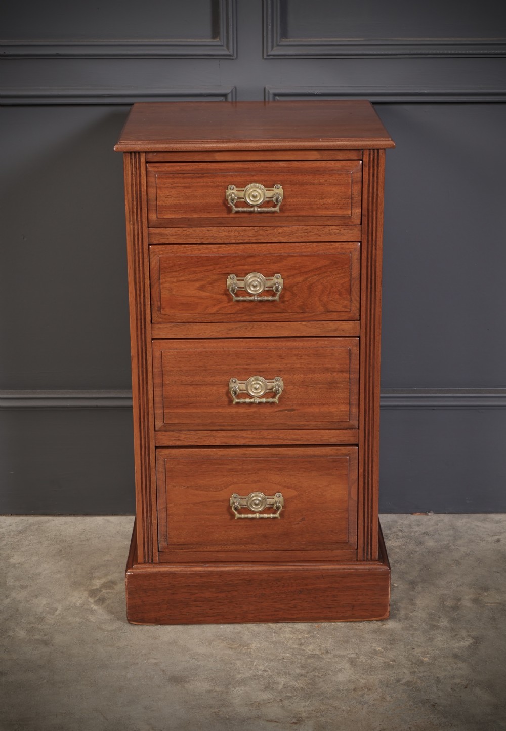 A pair of late Victorian walnut bedside chests, each featuring four drawers with ornamental brass handles on a plinth base. View VI