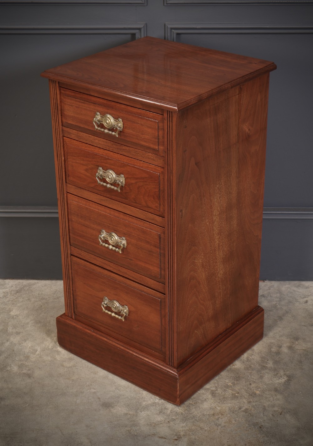 A pair of late Victorian walnut bedside chests, each featuring four drawers with ornamental brass handles on a plinth base. View VII