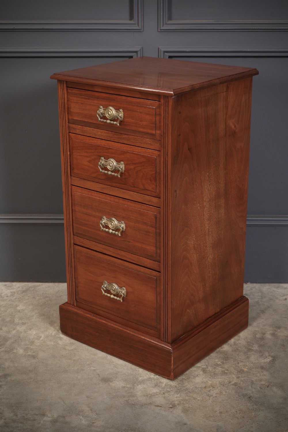 A pair of late Victorian walnut bedside chests, each featuring four drawers with ornamental brass handles on a plinth base. View VIII