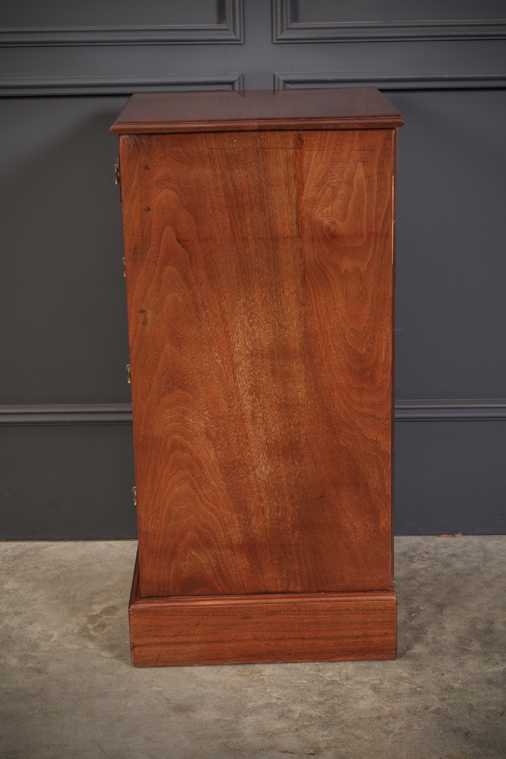 A pair of late Victorian walnut bedside chests, each featuring four drawers with ornamental brass handles on a plinth base. View X