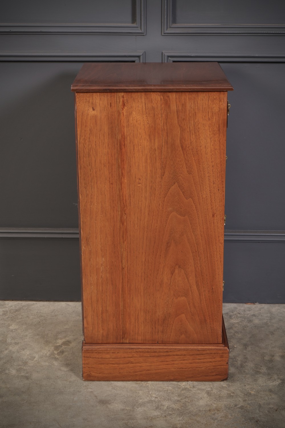 A pair of late Victorian walnut bedside chests, each featuring four drawers with ornamental brass handles on a plinth base. View XII