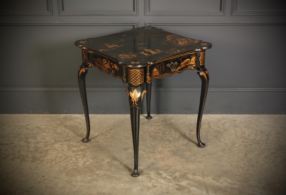 A black lacquered occasional table with gilded Chinoiserie scenes, a scalloped rim, and cabriole legs.
