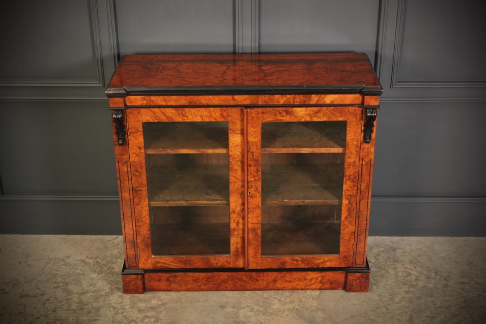 A low Victorian bookcase constructed from figured walnut wood featuring two glazed glass doors, black carved corbels, and internal timber shelves. View XI