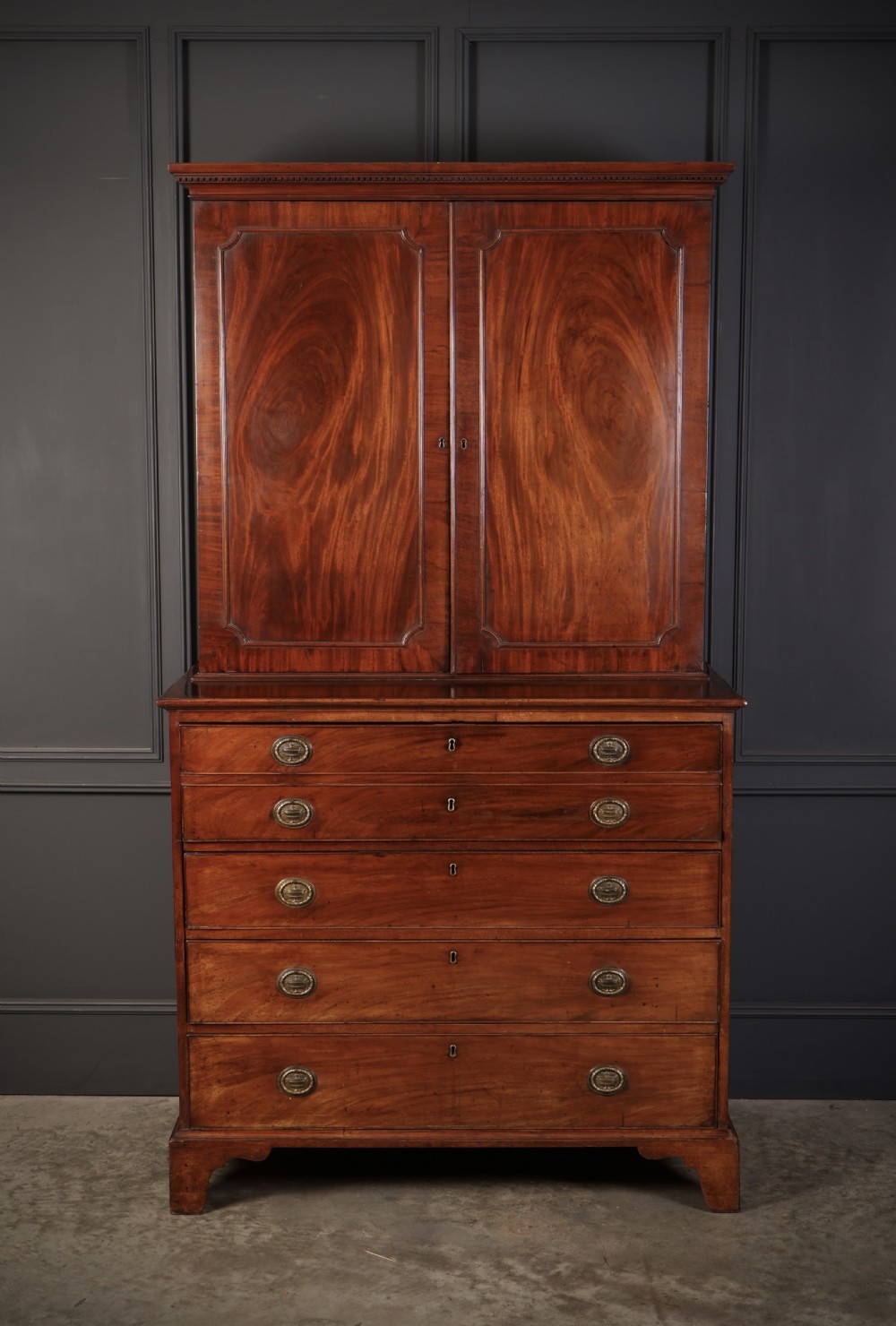 A George III mahogany secretaire cabinet featuring a twin panelled cupboard top over a lower chest of drawers with bracket feet. View II