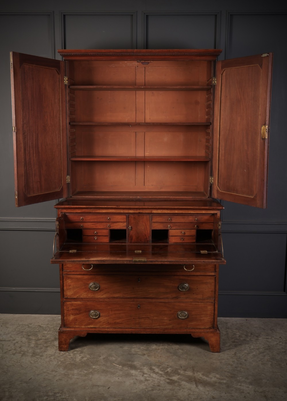 A George III mahogany secretaire cabinet featuring a twin panelled cupboard top over a lower chest of drawers with bracket feet. View III