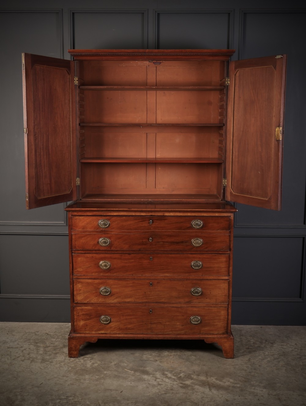 A George III mahogany secretaire cabinet featuring a twin panelled cupboard top over a lower chest of drawers with bracket feet. View V