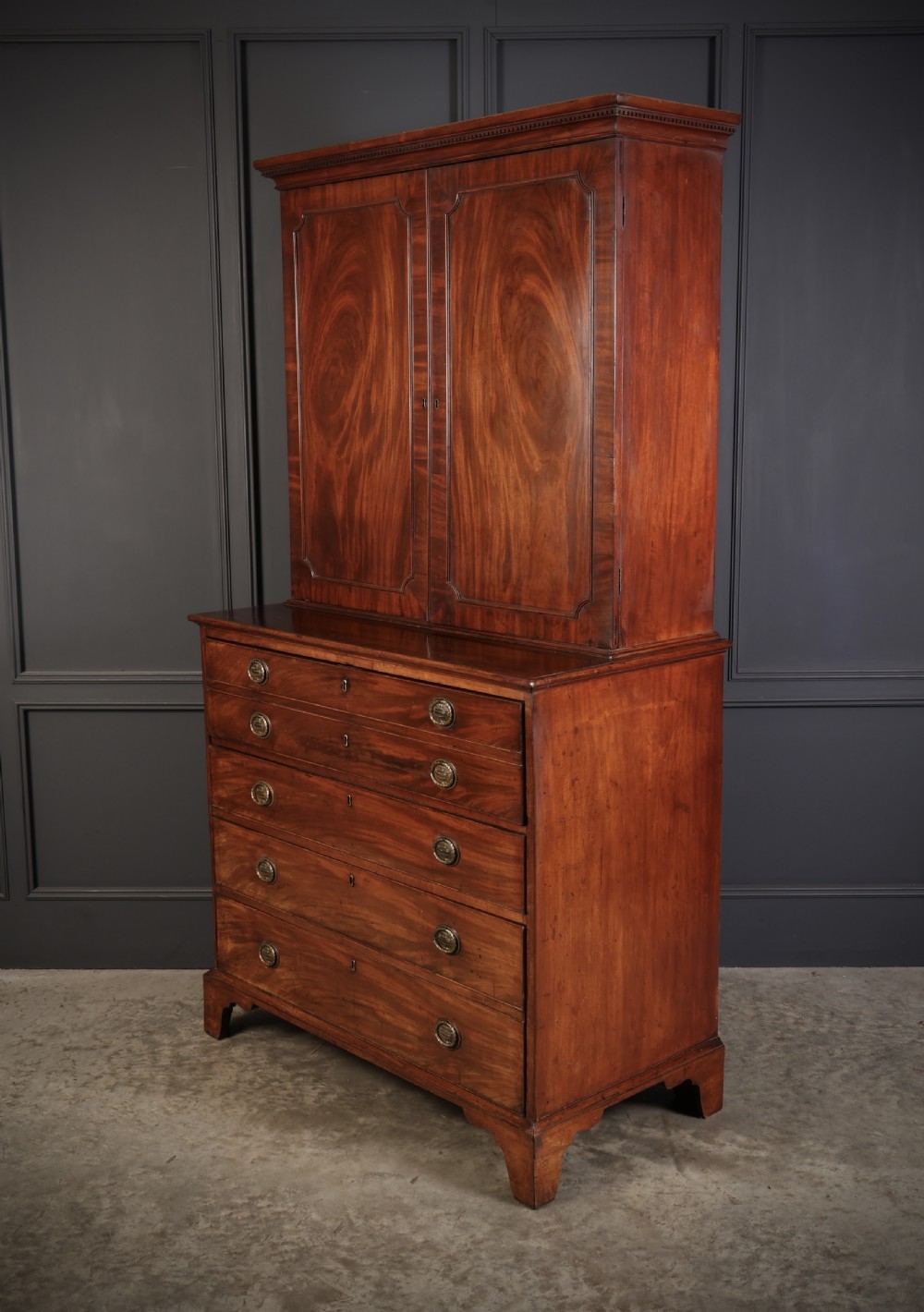 A George III mahogany secretaire cabinet featuring a twin panelled cupboard top over a lower chest of drawers with bracket feet. View VII