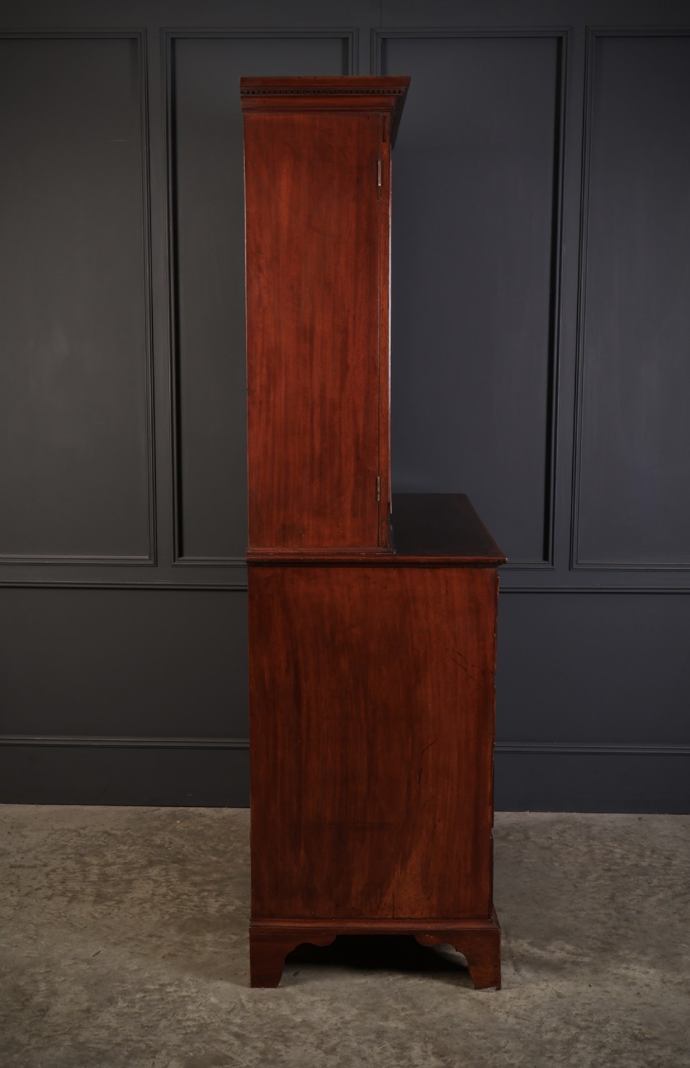A George III mahogany secretaire cabinet featuring a twin panelled cupboard top over a lower chest of drawers with bracket feet. View X