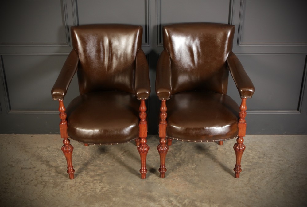 A pair of Victorian mahogany library armchairs upholstered in dark brown leather with brass studding and turned front legs. View II