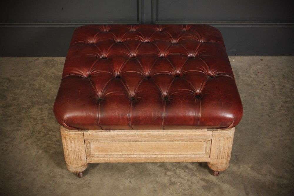 A large square Victorian footstool with deep-buttoned reddish-brown leather upholstery set within a carved light oak frame on castors. View III