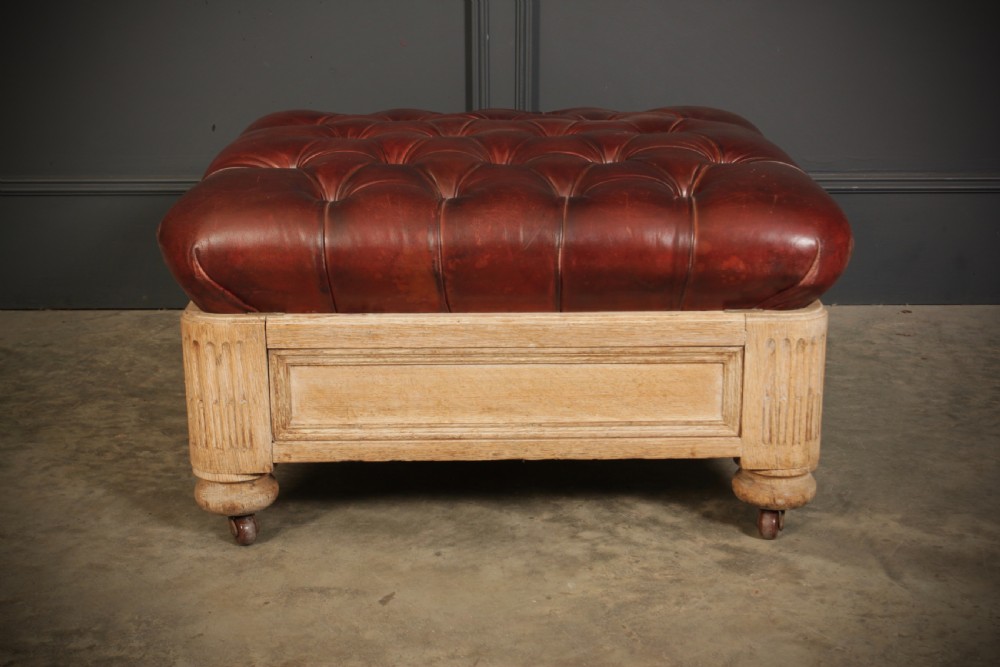 A large square Victorian footstool with deep-buttoned reddish-brown leather upholstery set within a carved light oak frame on castors. View IV