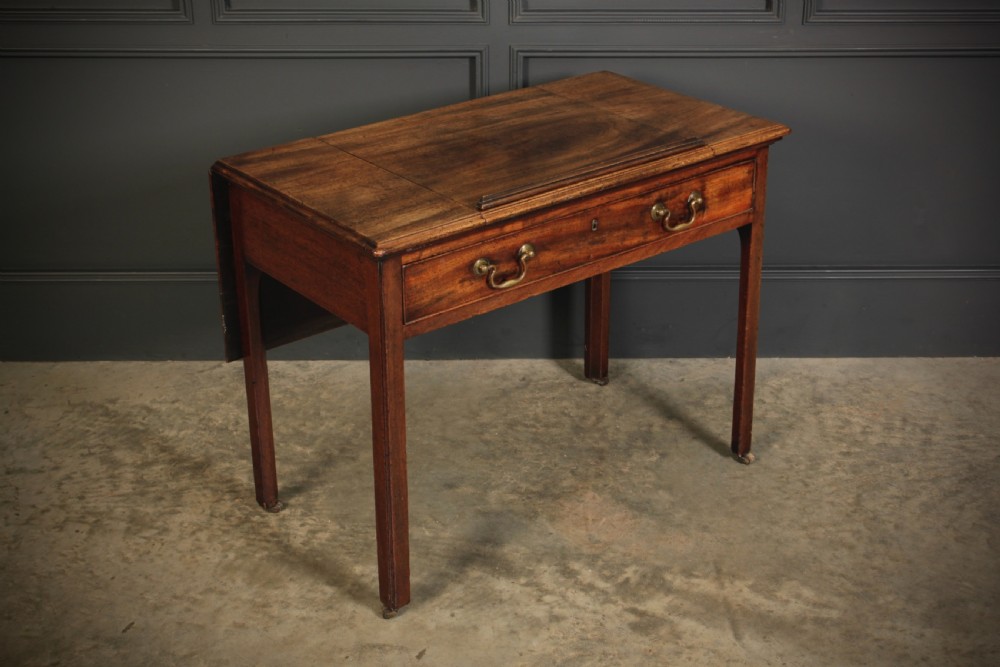 A Georgian mahogany architects table with a hinged adjustable writing slope top, a single drawer with brass swan-neck handles, and straight square legs fitted with brass castors. View II