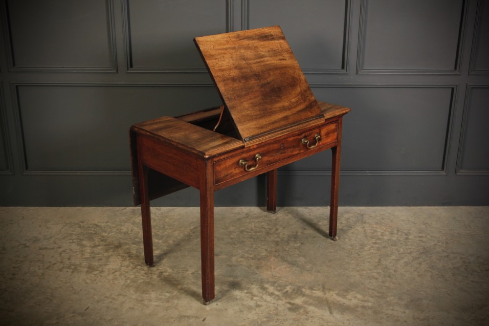 A Georgian mahogany architects table with a hinged adjustable writing slope top, a single drawer with brass swan-neck handles, and straight square legs fitted with brass castors. View III