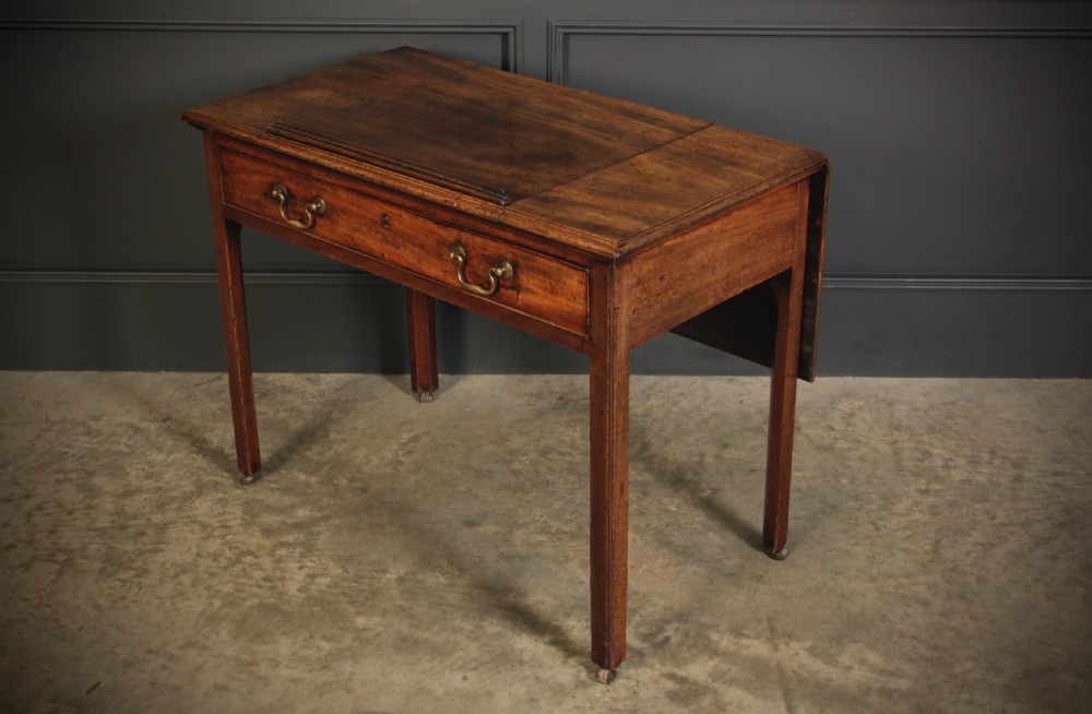 A Georgian mahogany architects table with a hinged adjustable writing slope top, a single drawer with brass swan-neck handles, and straight square legs fitted with brass castors. View XIV
