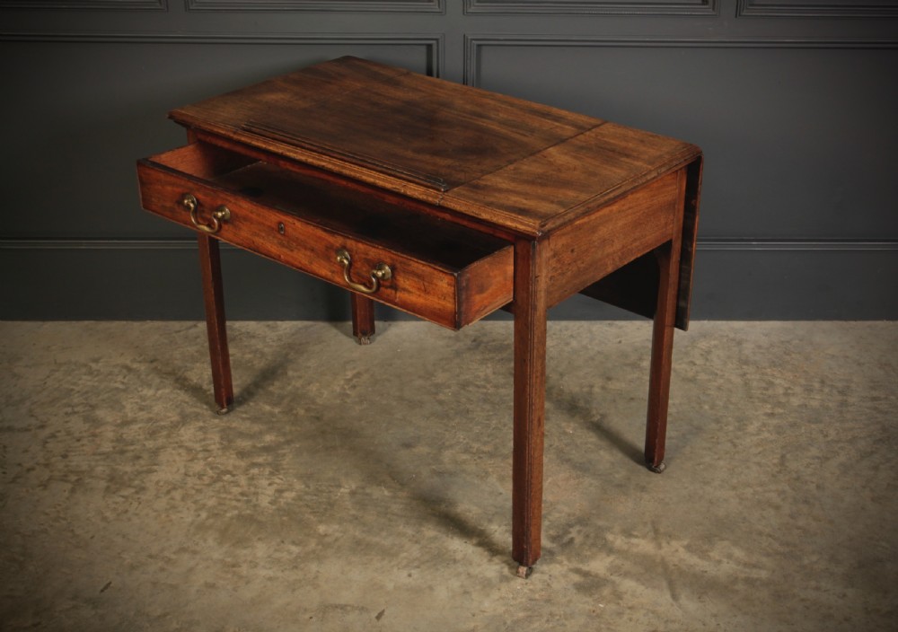 A Georgian mahogany architects table with a hinged adjustable writing slope top, a single drawer with brass swan-neck handles, and straight square legs fitted with brass castors. View XV