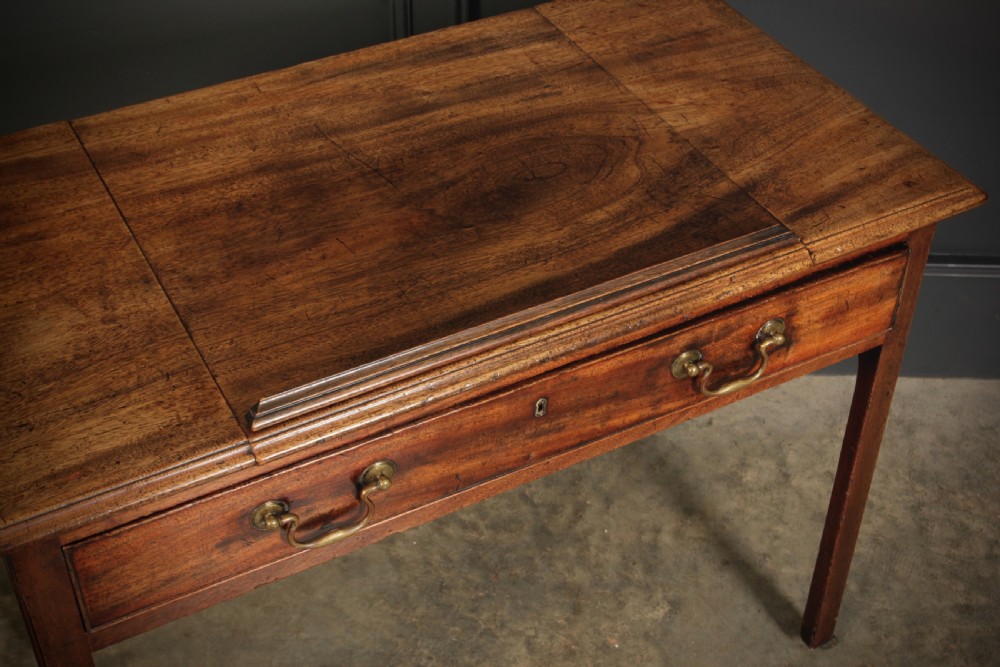 A Georgian mahogany architects table with a hinged adjustable writing slope top, a single drawer with brass swan-neck handles, and straight square legs fitted with brass castors. View XVIII
