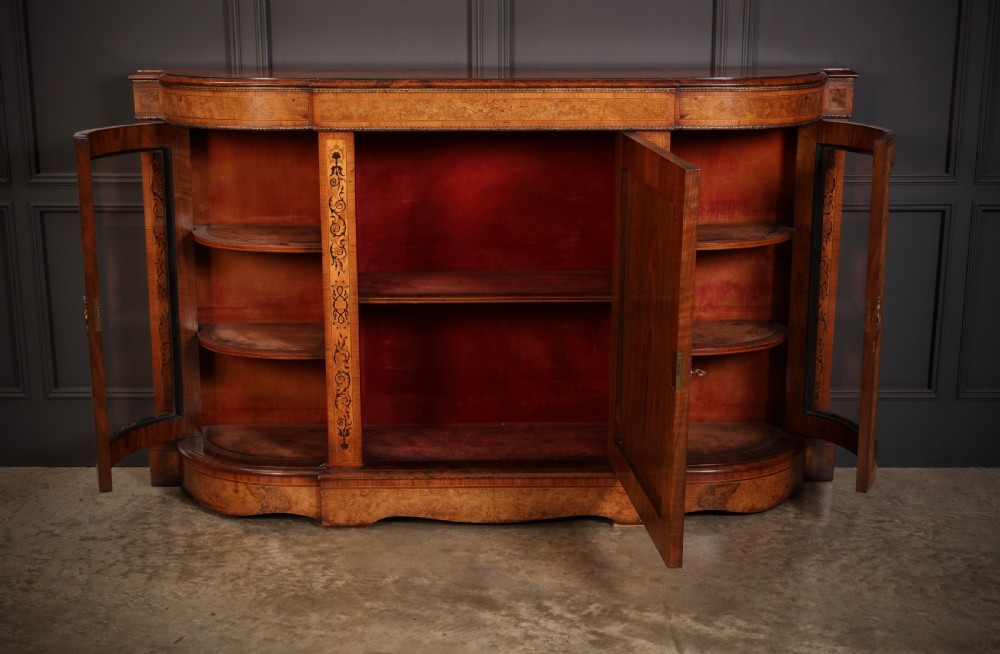 A nineteenth-century Victorian credenza made from burr walnut featuring central floral marquetry, curved glazed side display doors, and polished metal mounts. View II