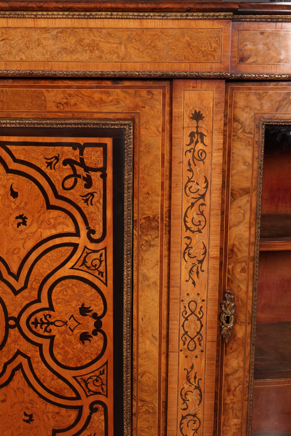 A nineteenth-century Victorian credenza made from burr walnut featuring central floral marquetry, curved glazed side display doors, and polished metal mounts. View III