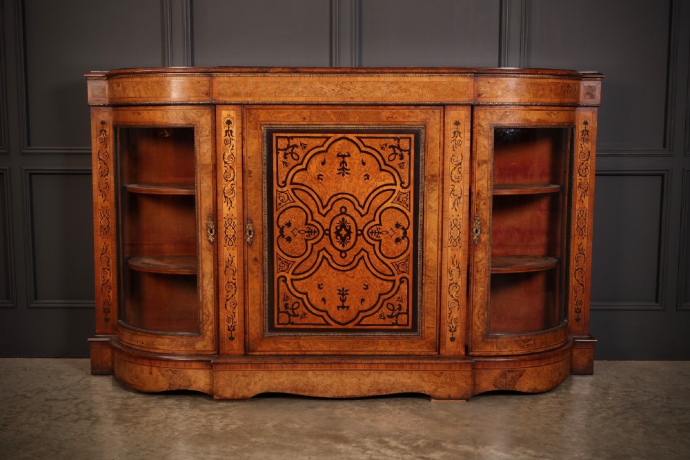 A nineteenth-century Victorian credenza made from burr walnut featuring central floral marquetry, curved glazed side display doors, and polished metal mounts.