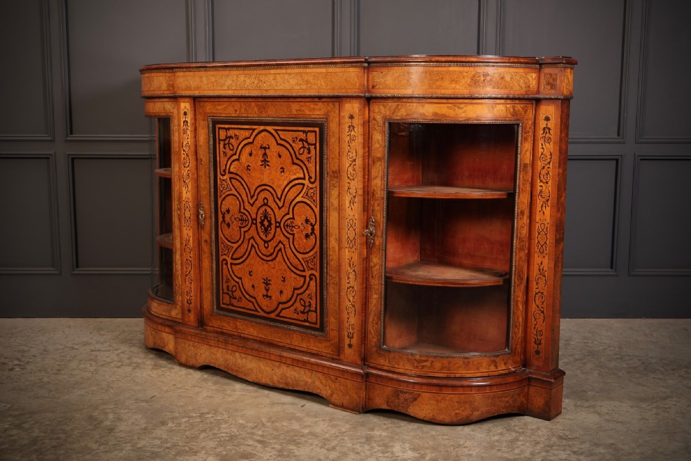 A nineteenth-century Victorian credenza made from burr walnut featuring central floral marquetry, curved glazed side display doors, and polished metal mounts. View VII