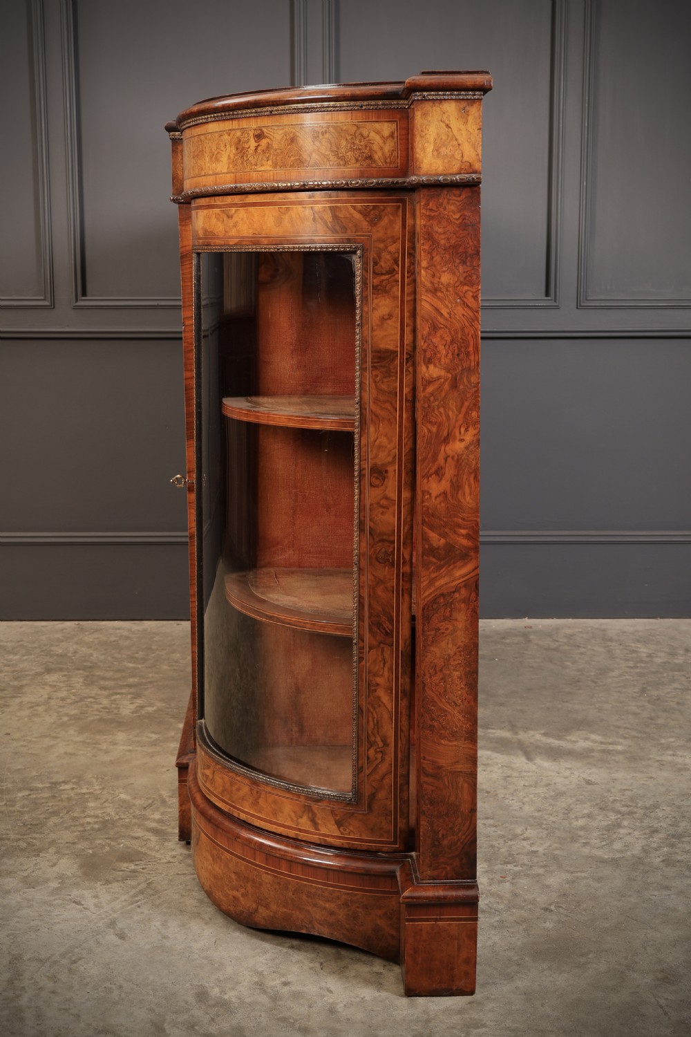 A nineteenth-century Victorian credenza made from burr walnut featuring central floral marquetry, curved glazed side display doors, and polished metal mounts. View VIII