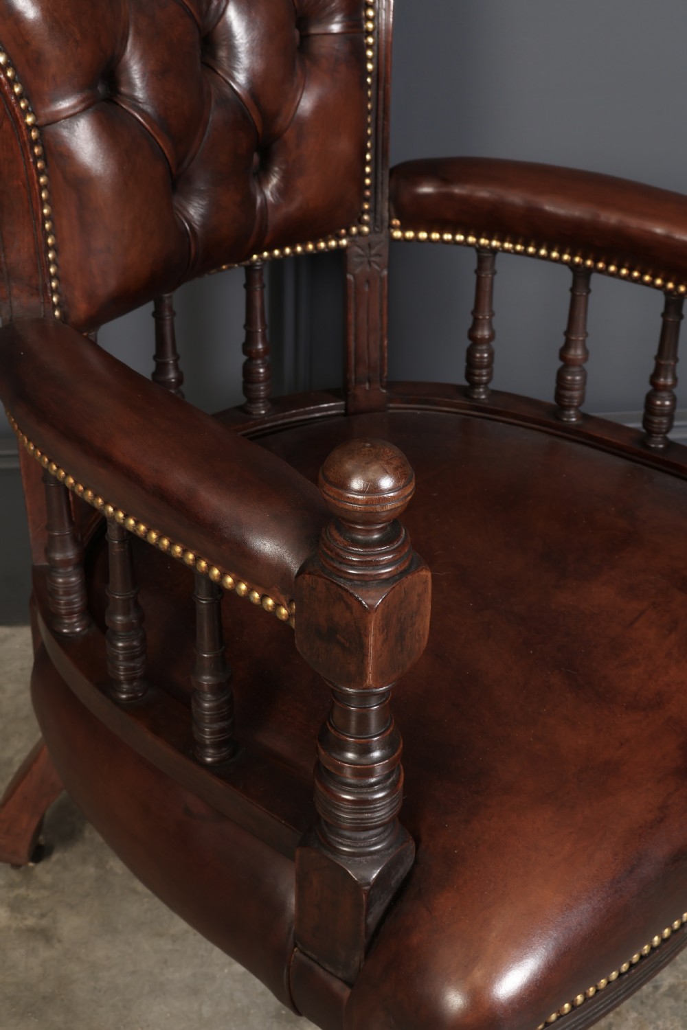 A pair of Victorian mahogany captains desk chairs upholstered in buttoned brown leather with stud detailing and turned legs on castors. View III