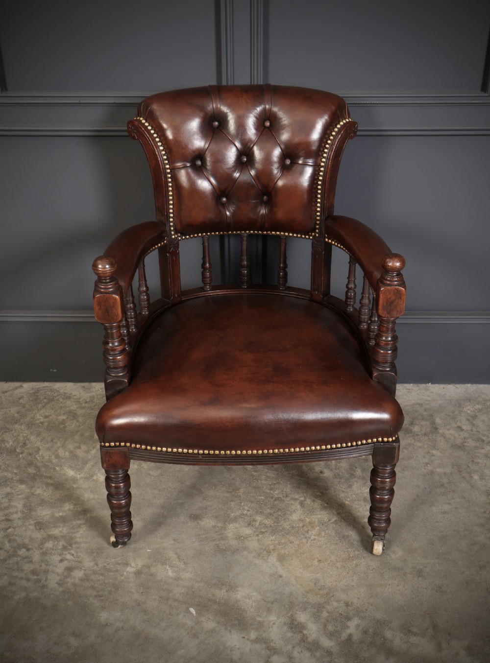 A pair of Victorian mahogany captains desk chairs upholstered in buttoned brown leather with stud detailing and turned legs on castors. View VII