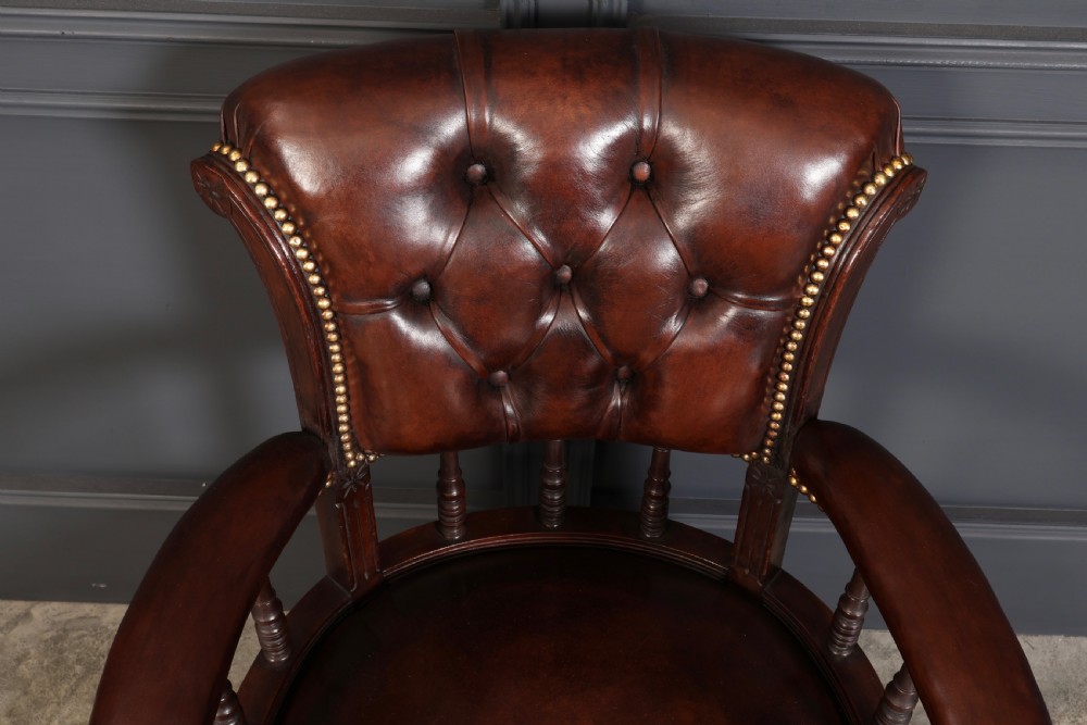 A pair of Victorian mahogany captains desk chairs upholstered in buttoned brown leather with stud detailing and turned legs on castors. View VIII