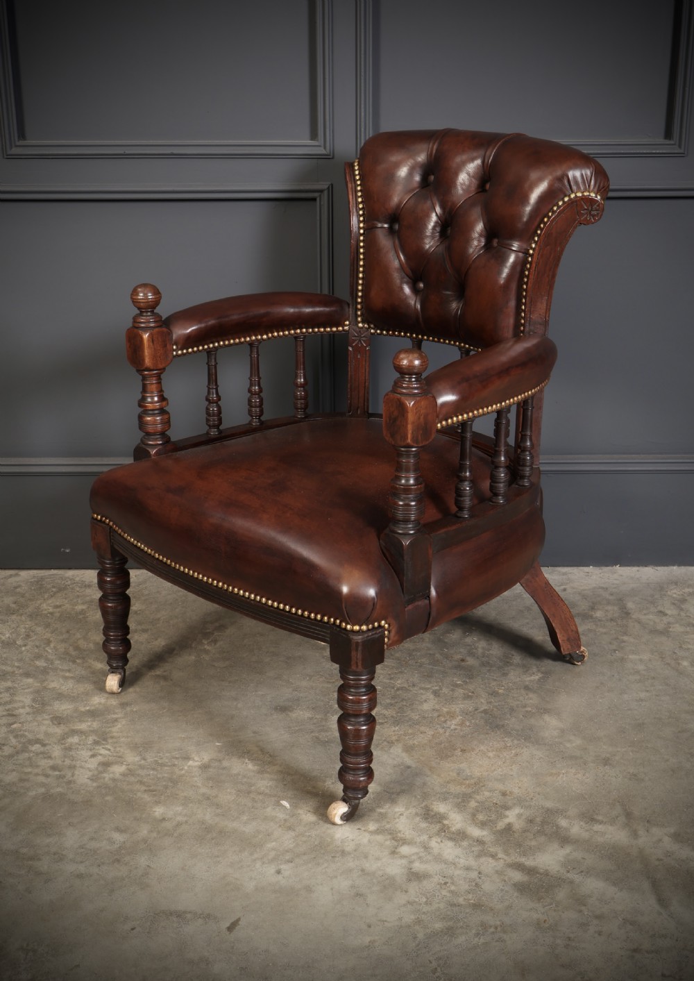 A pair of Victorian mahogany captains desk chairs upholstered in buttoned brown leather with stud detailing and turned legs on castors. View IX