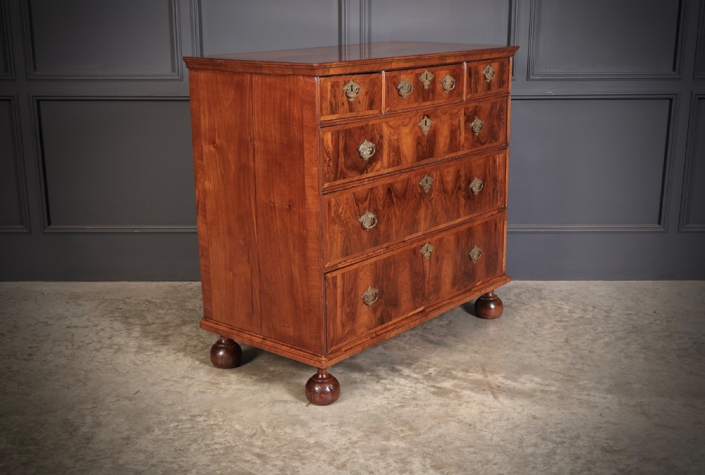 A Queen Anne style warm brown walnut chest of drawers featuring inlaid geometric top decoration, brass drop handles, keyhole escutcheons, and turned bun feet. View III