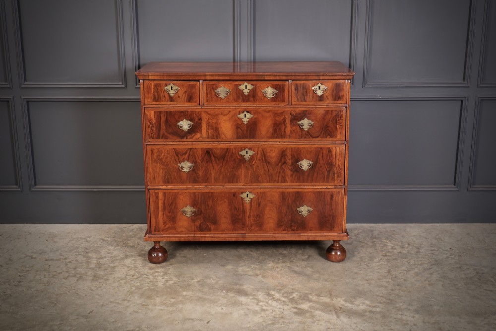 A Queen Anne style warm brown walnut chest of drawers featuring inlaid geometric top decoration, brass drop handles, keyhole escutcheons, and turned bun feet. View V