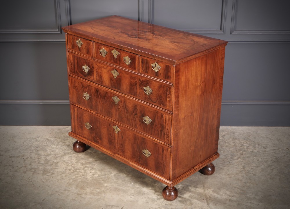 A Queen Anne style warm brown walnut chest of drawers featuring inlaid geometric top decoration, brass drop handles, keyhole escutcheons, and turned bun feet. View VI