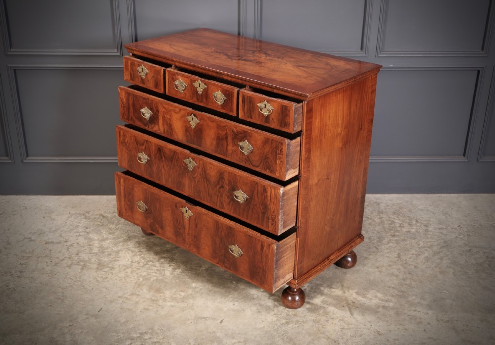 A Queen Anne style warm brown walnut chest of drawers featuring inlaid geometric top decoration, brass drop handles, keyhole escutcheons, and turned bun feet. View VIII