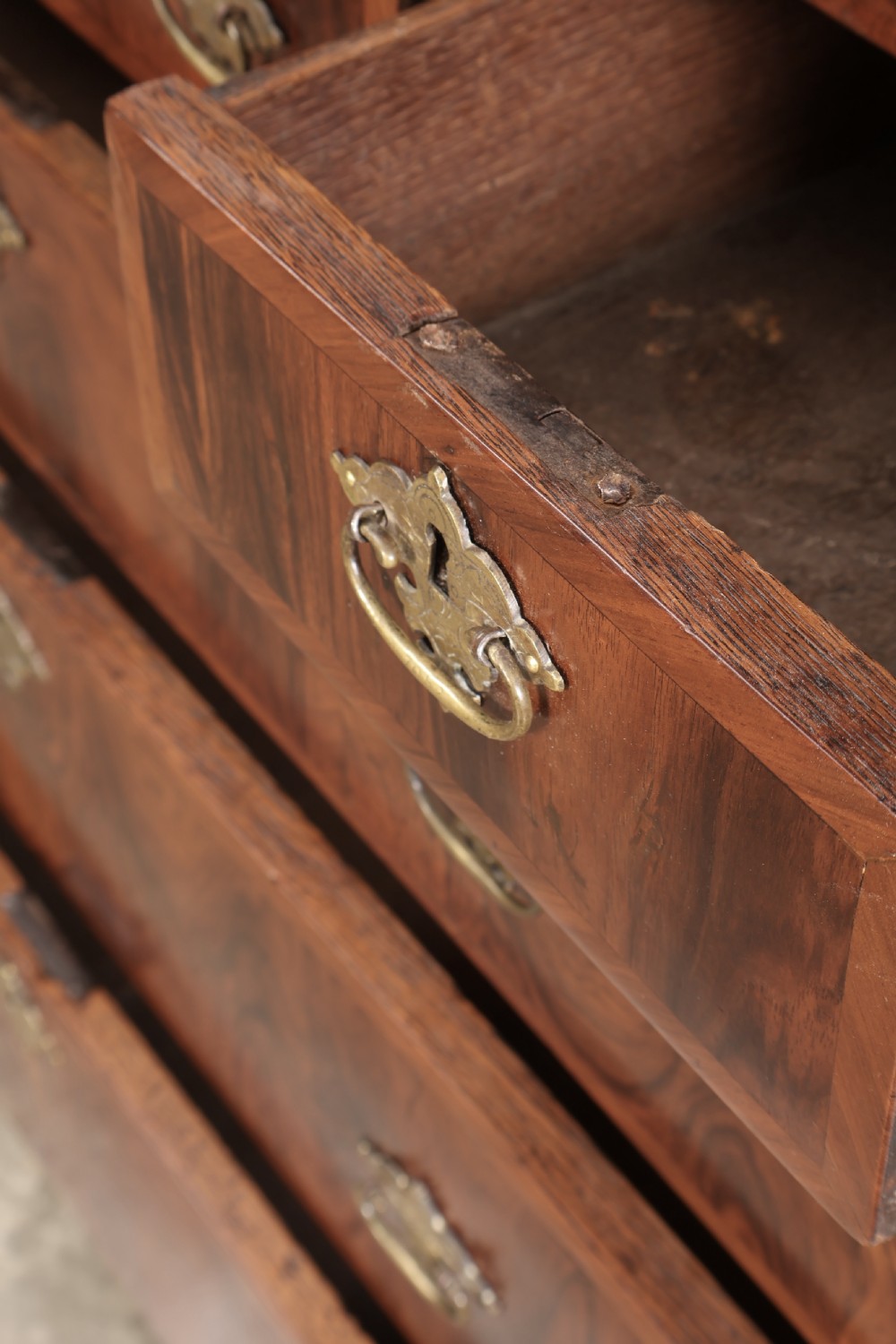 A Queen Anne style warm brown walnut chest of drawers featuring inlaid geometric top decoration, brass drop handles, keyhole escutcheons, and turned bun feet. View XI